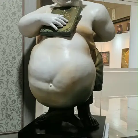 Patung putih sosok pria memeluk kitab